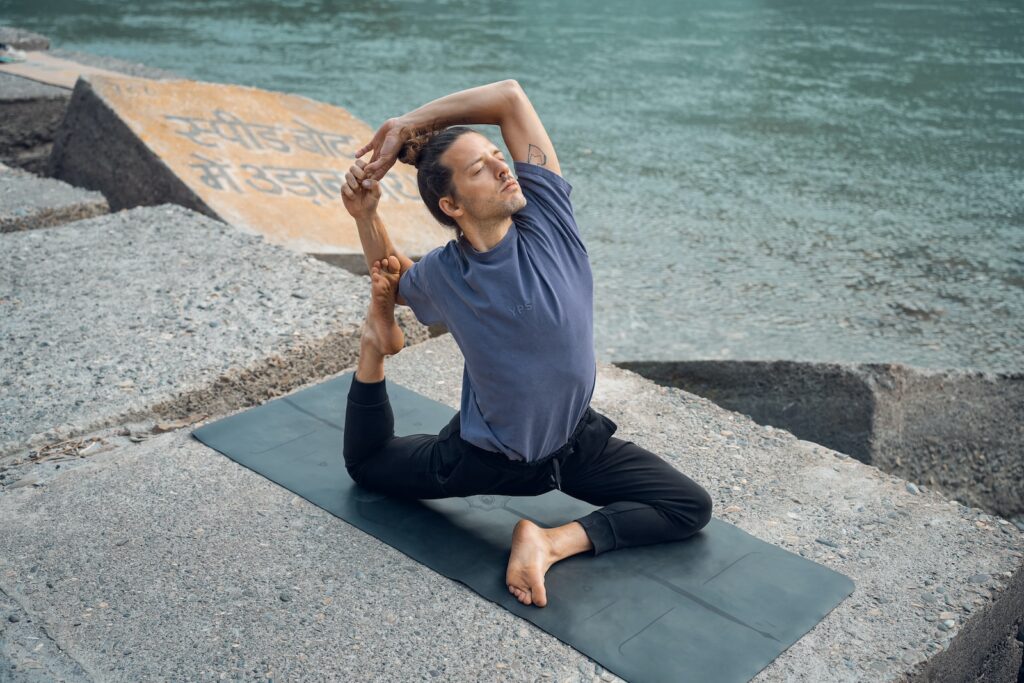 a man sitting on a yoga mat in front of a body of water